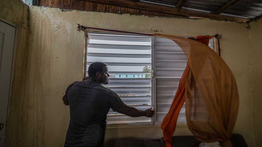 Puerto Rico Tropical Weather Nelson Cirino secures the windows of his home as the winds of Hurricane Fiona blow in Loiza, Puerto Rico, Sunday, Sept. 18, 2022.
